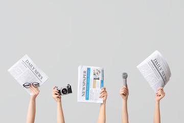 Female hands with newspapers, photo camera and microphone on grey background