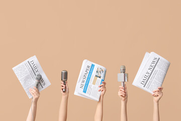 Female hands with microphones and newspapers against color background