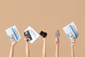 Female hands with newspapers, microphone, photo camera and old video cassette on color background