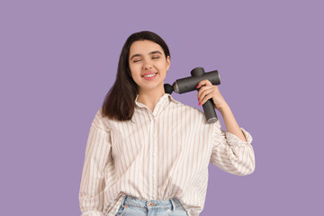 Young woman massaging her neck with percussive massager on lilac background