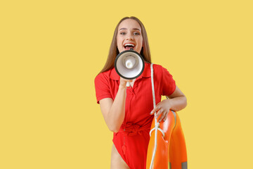 Young female lifeguard with rescue ring and megaphone on yellow background