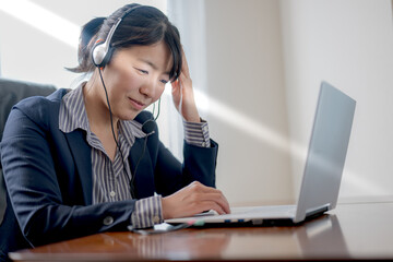 ヘッドホンとPCとスーツ女性