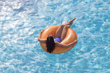 A woman in a swimming pool relaxing on an inflatable ring