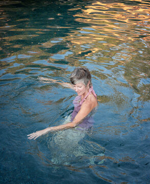 Woman with short grey hair relaxing in a beautiful swimming pool
