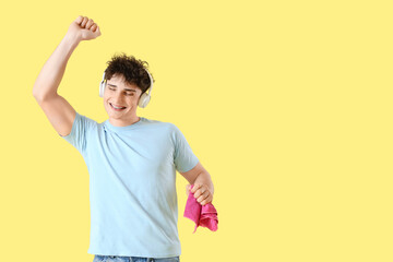 Young man in headphones with rag on yellow background