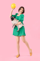 Young woman with cute pug dog and frisbee disk on pink background