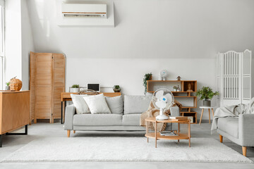 Interior of light living room with modern electric fan on coffee table