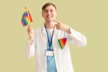 Male dentist pointing at LGBT flag on green background