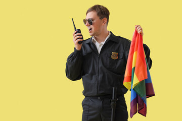 Male police officer with LGBT flag and two-way radio on yellow background