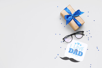 Eyeglasses, paper mustache, gift box and paper with text I LOVE DAD on white background. Father's...