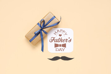 Paper mustache, gift box and greeting card with text HAPPY FATHER'S DAY on beige background. Top view