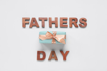 Gift box and text FATHERS DAY made with wooden letters on white background. Top view