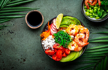 Poke bowl for balanced diet with shrimp, rice, avocado, vegetables and chuka salad, green table...