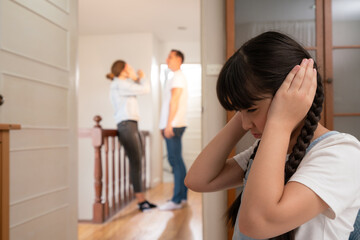Stressed and unhappy young girl huddle in corner, cover her ears blocking sound of her parent...