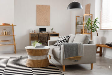 Interior of stylish living room with grey sofa, coffee table, workplace and shelving unit