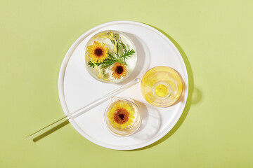 A white ceramic dish features laboratory glassware filled with liquid, green leaves and Calendula flowers. Calendula flowers helps reduce sensitivity and soothe irritation