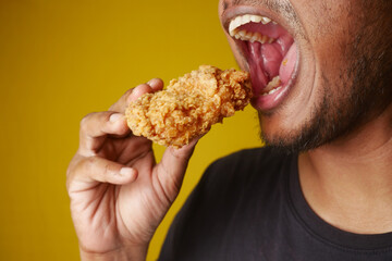 Man enjoying fried chicken, mouth open, savoring every bite with a big smile