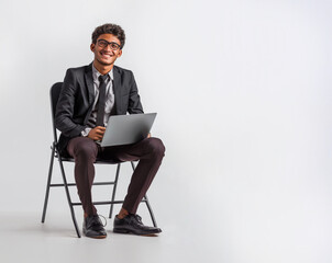 Successful entrepreneur sitting with laptop, dressed in suit, isolated in white
