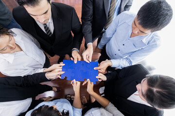 Top view multiethnic business people holding jigsaw pieces and merge them together as effective...