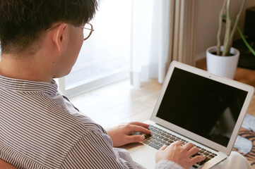 リビングでパソコンを使っている若い男性