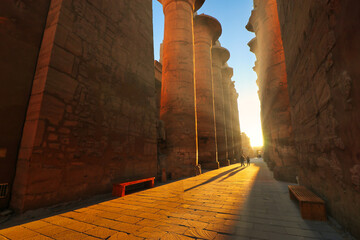 Golden morning sunlight fills the central passage of the Great Temple of Karnak illuminating...