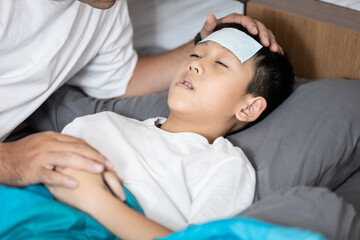 Child boy suffering from flu,influenza virus,fever and cold,kid has cooling gel on forehead,rest...