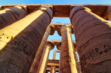 Magnificent hypostyle columns of the Karnak temple with painted lintel ceiling slabs are a...