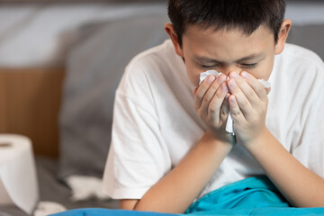 Sick child boy having allergies,hay fever,runny nose,sneezing,nasal congestion,blow the nose with...