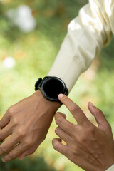 Close up smart watch on female hand in summer park. Round display with apps for hiking and sports...