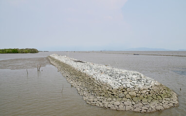 Walls of large and small rocks line the beach to protect the beach and land from waves, breakwater...