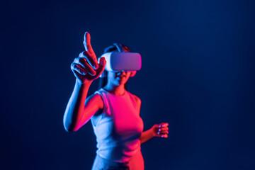Smart female standing in cyberpunk neon light wear VR headset connecting metaverse, futuristic...