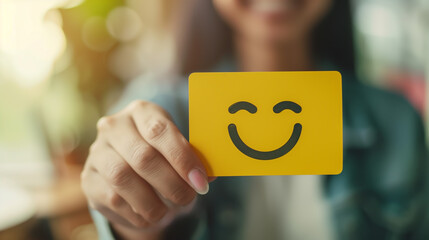Young Asian woman presenting a yellow card with a happy smiling face, blurred office background, Concept of customer satisfaction, positive feedback, and happy client interaction.