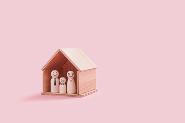 Happy wooden family figures inside a tiny wooden house isolated on a pink background. Parent and...
