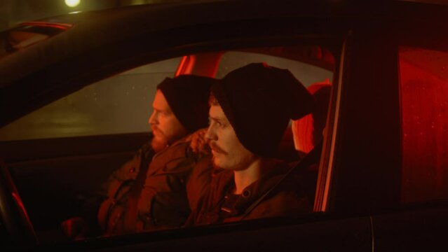 Two men in a car lowering ski masks over their faces