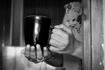 Hand holding a mug in the window frame welcoming the morning