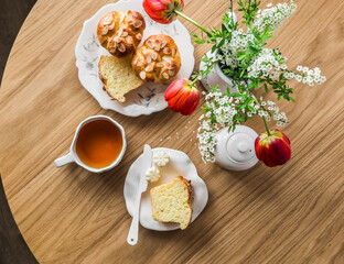 Cozy morning - breakfast served with fresh brioche rolls, tea, a bouquet of flowers on a round wooden table