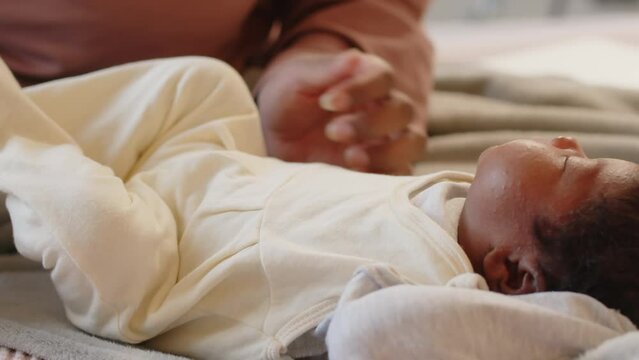 Cropped shot of caring mother stroking her little baby on belly, lying on soft blanket in bed and awakening from sleepCropped shot of caring mother stroking her little baby on belly, lying on soft bla