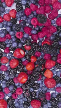 Mix of red blue and black berries dropping in epic slow motion 