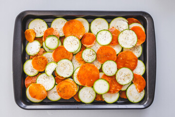 zucchini and sweet potato slices on oven tray with seasoning