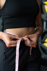 Close-up of young indian fitness girl measuring her waist. weight loss and dieting concept.