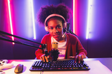 Host channel of gaming streamer, African girl taking, typing with Esport skilled team player and viewers online game in neon color lighting room. Concept of cybersport indoor activities. Tastemaker.