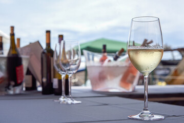 Glass of fresh white wine at its temperature on a table with a blurred background with bottles of various wines