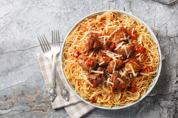 Stewed beef in a spicy wine tomato sauce served with spaghetti close-up in a plate on the table....