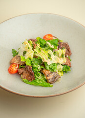 hot salad with beef, mushrooms and cherry tomatoes on the background