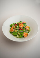 green salad with shrimp and chili pepper on a gray background