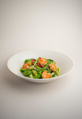 green salad with shrimp and chili pepper on a gray background