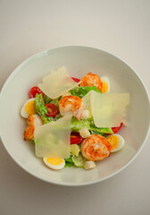 Caesar with shrimp and parmesan on a gray background