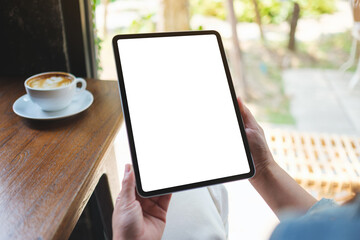 Mockup image of a woman holding digital tablet with blank white desktop screen in cafe - Powered by Adobe