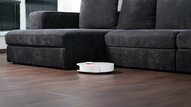 Robot vacuum cleaner removing dirt from floor in room. Smart home with automated devices that simplify life.