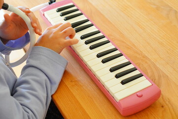 小学4年生の女の子が鍵盤ハーモニカを演奏している様子。
